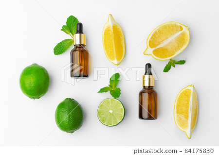 Essential oil bottles and citrus fruit on white background 84175830