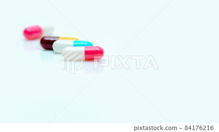 Selective focus on antibiotic capsule pill. Pharmaceutical industry. Prescription drugs. Pharmacy web banner. Pink, blue, yellow, red capsules pill on white background. Antibiotic drug resistance. 84176216