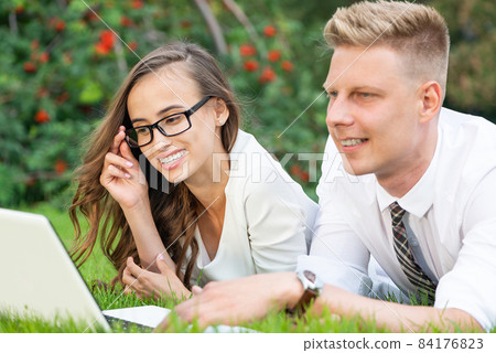 businessman and businesswoman with a laptop in a city park businessman and businesswoman with a laptop in a city park 84176823