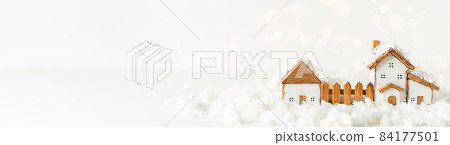 Happy New Year and Merry Christmas banner. Festive white background with toy wooden house, snow, light bokeh, christmas tree, village and decoration. Copy space for winter holidays greeting card 84177501