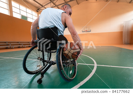 Close up photo of wheelchairs and handicapped war veterans playing basketball on the court 84177662