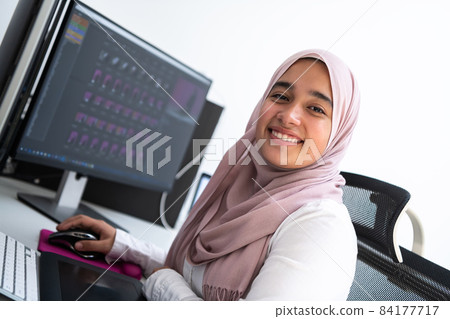 Female Arabic creative professional working at home office on desktop computer with dual screen monitor top view. Selectve focus Female Arabic creative professional working at home office on desktop computer with dual screen monitor top view. Selectve focus 84177717