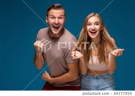 Overjoyed woman and man raise fists with triumph, have successful deal, exclaim joyfully, on blue background. Overjoyed woman and man raise fists with triumph, have successful deal, exclaim joyfully, on blue background. 84177859
