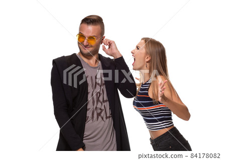 Angry blonde young European woman gestures with hands, shouts at husband who is guilty, stands together against white background, have dispute and quarrel Angry blonde young European woman gestures with hands, shouts at husband who is guilty, stands together against white background, have dispute and quarrel 84178082
