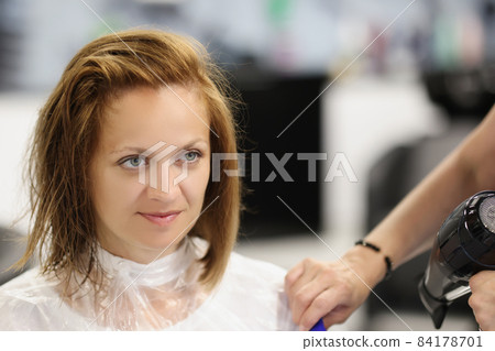 Client woman after refreshing haircut looking in mirror on herself Client woman after refreshing haircut looking in mirror on herself 84178701