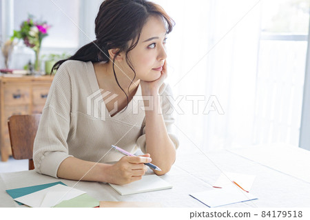 Young woman writing a letter by the window Young woman writing a letter by the window 84179518