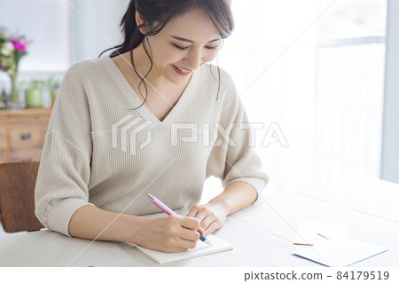 Young woman writing a letter by the window Young woman writing a letter by the window 84179519