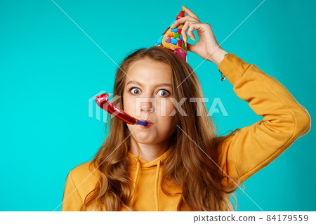 Young casual woman in party cone with horn Young casual woman in party cone with horn 84179559
