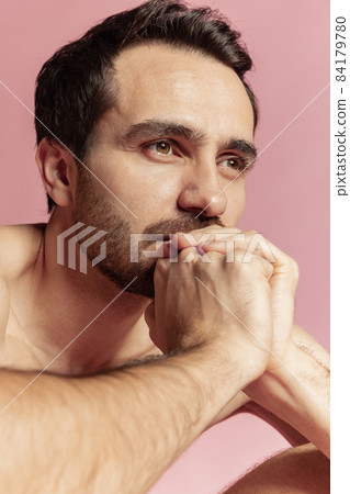 Close-up portrait of young handsome bearded shirtless man isolated on pink studio background. Natural beauty 84179780