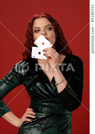 Young sexy woman with a red curly hair holding aces, on a red background. Poker Young sexy woman with a red curly hair holding aces, on a red background. Poker 84180352