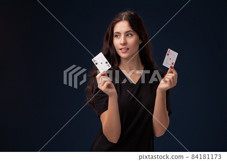 Curly hair brunette is posing with playing cards in her hands. Poker concept on a black background. Casino. Curly hair brunette is posing with playing cards in her hands. Poker concept on a black background. Casino. 84181173