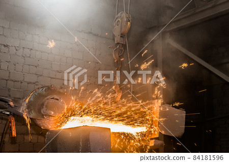 Heavy grinding equipment suspended on a chain with a hook processes and cleans cast iron reinforced concrete tubing in the workshop of an industrial plant Heavy grinding equipment suspended on a chain with a hook processes and cleans cast iron reinforced concrete tubing in the workshop of an industrial plant 84181596