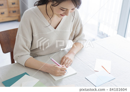 Young woman writing a letter by the window Young woman writing a letter by the window 84181604