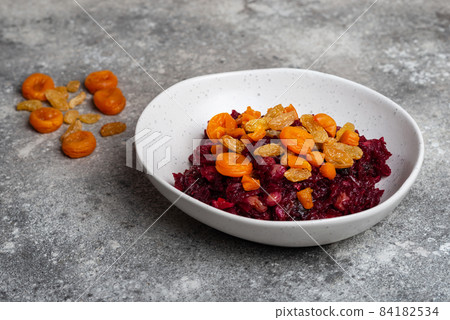 Beetroot salad with prunes in plate vegan food close-up on grey background Beetroot salad with prunes in plate vegan food close-up on grey background 84182534