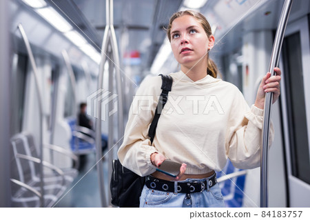 Portrait of woman holding smart phone in a subway train Portrait of woman holding smart phone in a subway train 84183757