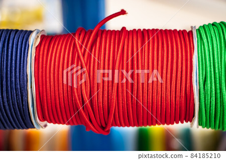 Spool of red sewing elastic band closeup. Material for a hobby. 84185210