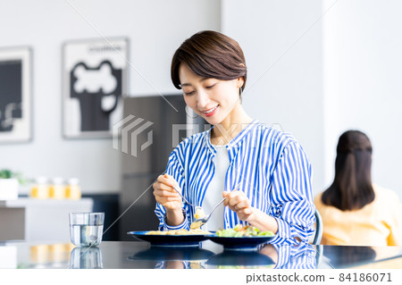 Middle-aged woman eating pasta at lunch Middle-aged woman eating pasta at lunch 84186071