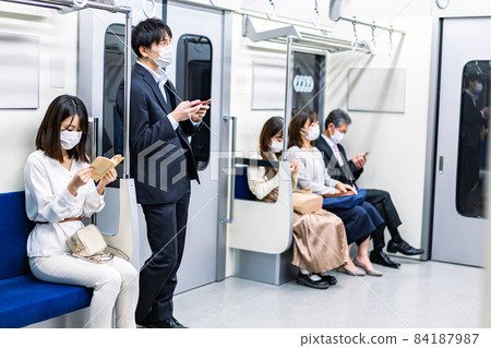 People wearing masks and getting on the train People wearing masks and getting on the train 84187987