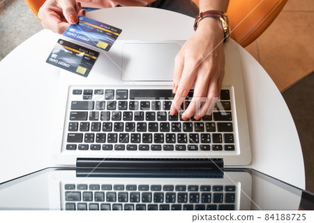 Top view of someone hand holding credit card during using laptop for online shopping. Online shopping is the process of buying goods and services from merchants over the Internet. Top view of someone hand holding credit card during using laptop for online shopping. Online shopping is the process of buying goods and services from merchants over the Internet. 84188725