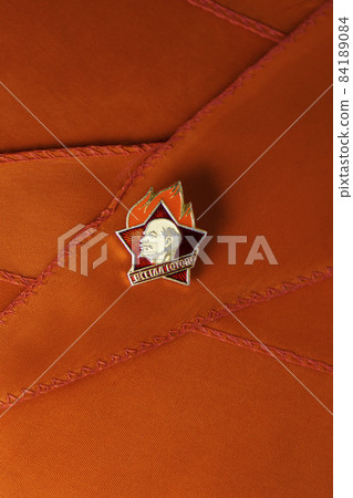 Retro Soviet pioneer badge with profile of Lenin on a red pioneer tie Retro Soviet pioneer badge with profile of Lenin on a red pioneer tie 84189084