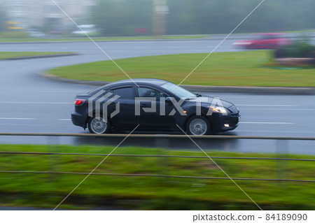 Car drives on city street on wet asphalt at foggy summer day 84189090