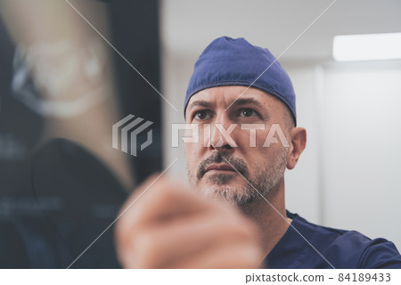 Orthopedist doctor examining X-ray picture in hospital or clinic  84189433