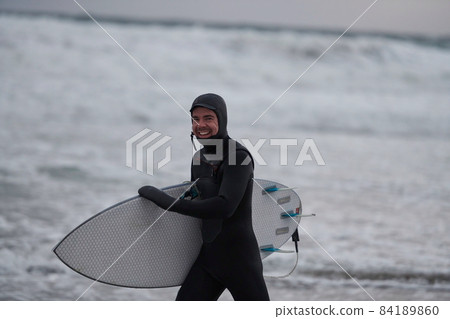 Arctic surfer going by beach after surfing Arctic surfer going by beach after surfing 84189860