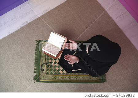 Middle eastern woman praying and reading the holy Quran Middle eastern woman praying and reading the holy Quran 84189938