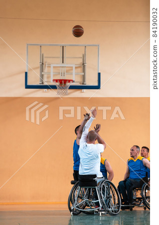 Disabled War veterans mixed race and age basketball teams in wheelchairs playing a training match in a sports gym hall. Handicapped people rehabilitation and inclusion concept Disabled War veterans mixed race and age basketball teams in wheelchairs playing a training match in a sports gym hall. Handicapped people rehabilitation and inclusion concept 84190032