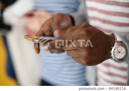 diverse teenagers use mobile devices while posing for a studio photo in front of a pink background 84190116