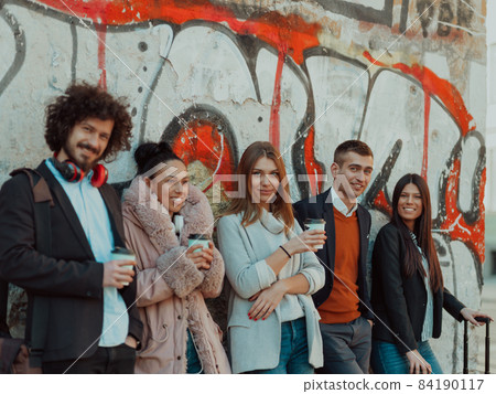 young people stand in front of a drawn wall in an abandoned street. young people stand in front of a drawn wall in an abandoned street. 84190117