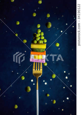 layers with ingredients of Russian salad Olivier on a fork 84190122