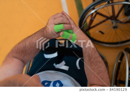 a disabled basketball player puts on a corset and bandages on his arms and fingers in preparation for a game in the arena 84190129