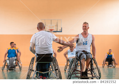 a team of war veterans in wheelchairs playing basketball, celebrating points won in a game. High five concept a team of war veterans in wheelchairs playing basketball, celebrating points won in a game. High five concept 84191552