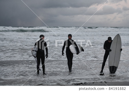 Arctic surfers going by beach after surfing 84191882