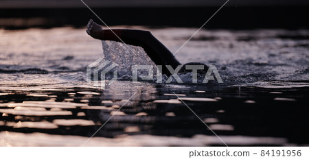 triathlon athlete swimming on lake in sunrise wearing wetsuit triathlon athlete swimming on lake in sunrise wearing wetsuit 84191956