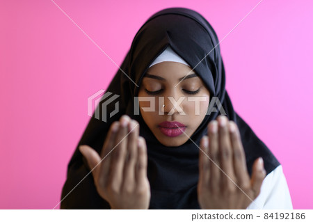 Modern African Muslim woman makes traditional prayer to God, keeps hands in praying gesture, wears traditional white clothes 84192186