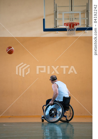 a war invalid in a wheelchair trains with a ball at a basketball club in training with professional sports equipment for the disabled. the concept of sport for people with disabilities a war invalid in a wheelchair trains with a ball at a basketball club in training with professional sports equipment for the disabled. the concept of sport for people with disabilities 84192242