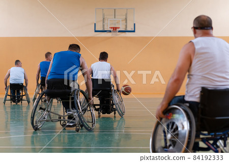 handicapped war veterans in wheelchairs with professional equipment play basketball match in the hall.the concept of sports with disabilities 84192333