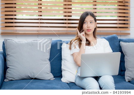 Beautiful young asian woman working on laptop computer and thinking idea on sofa. Beautiful young asian woman working on laptop computer and thinking idea on sofa. 84193994