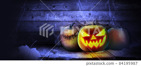 Scary Halloween pumpkin with eyes glowing inside on wooden background Scary Halloween pumpkin with eyes glowing inside on wooden background 84195987
