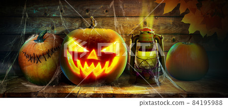Scary Halloween pumpkin with eyes glowing inside on wooden background Scary Halloween pumpkin with eyes glowing inside on wooden background 84195988