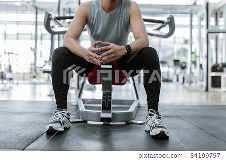 exercise concept The male broad-shoulder gym member resting on the weight machine after pulling down for several times exercise concept The male broad-shoulder gym member resting on the weight machine after pulling down for several times 84199797