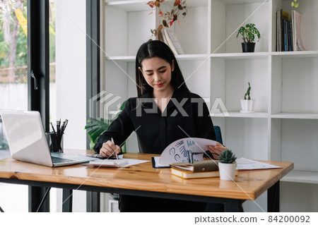 Portrait of Asian young female Businesswoman working on laptop computer doing finances,accounting analysis,report,data and pointing graph at the office Portrait of Asian young female Businesswoman working on laptop computer doing finances,accounting analysis,report,data and pointing graph at the office 84200092