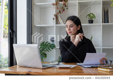 Business asian woman using smartphone for do math finance on wooden desk in office, tax, accounting, financial concept. 84200093