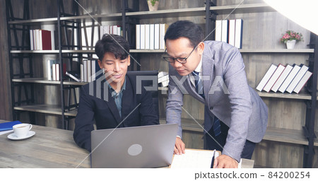 Businessman mentor coworker at office desk as team leader bossy manager. Two business people talking together start up new project planning strategy office meeting room. Businessman discuss, planning Businessman mentor coworker at office desk as team leader bossy manager. Two business people talking together start up new project planning strategy office meeting room. Businessman discuss, planning 84200254