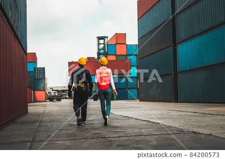 Industrial worker works with co-worker at overseas shipping container yard 84200573