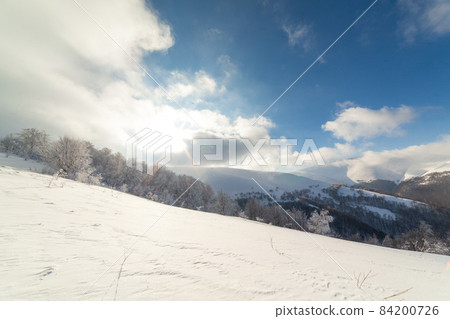 Beautiful landscape with the Carpathian mountains. Snow-capped mountain peaks from a height. A wonderful sky covers the snowy winter mountains. Ukraine Beautiful landscape with the Carpathian mountains. Snow-capped mountain peaks from a height. A wonderful sky covers the snowy winter mountains. Ukraine 84200726