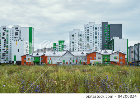 Modern construction, new neighborhood. Modern beautiful new buildings. Colored wall on the background of blue sky. 84200824