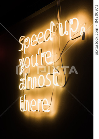 Neon yellow lettering on the wall speed up, you are almost there. High quality photo. neon lettering on the wall 84200973